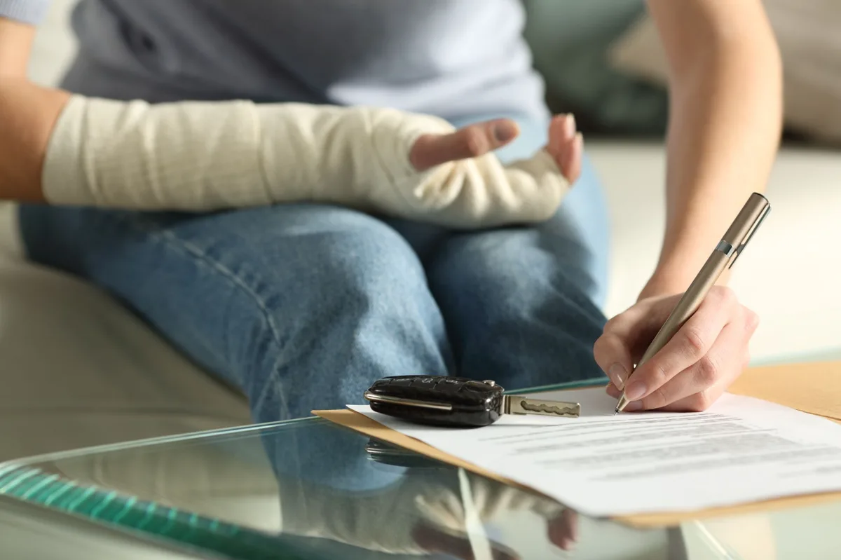 Signing an insurance claim form after a car accident, car key on the table
