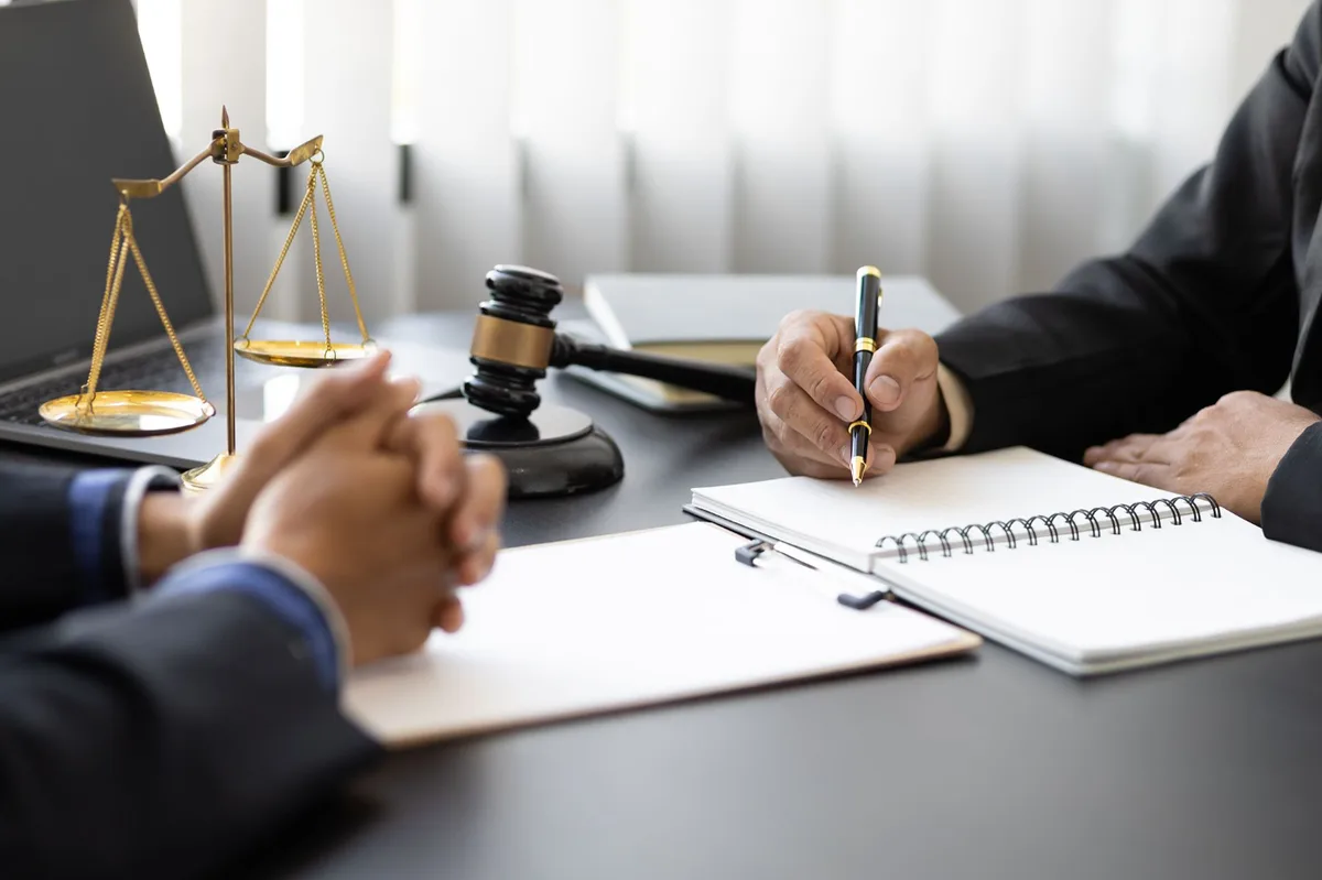 Attorney and client reviewing paperwork at a desk with a gavel and scales of justice