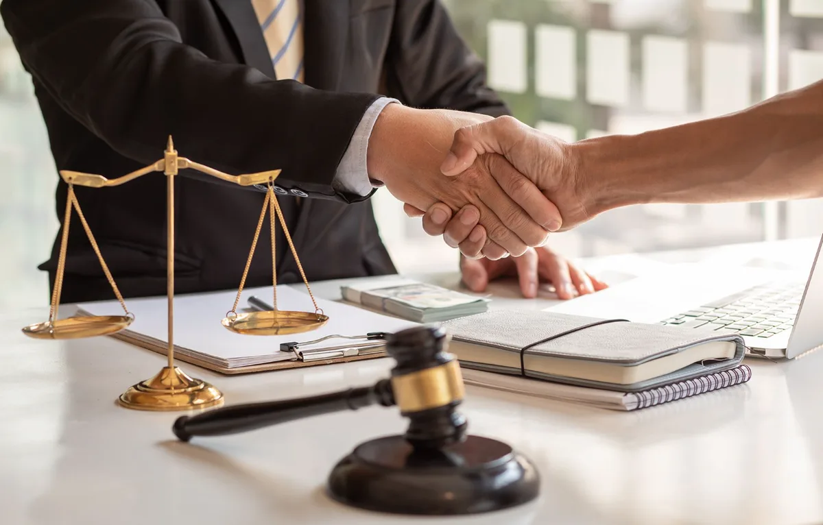 Attorney and client shaking hands over closing documents